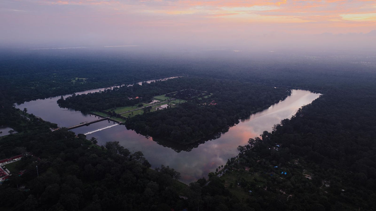Aerial view of Angkor Wat surrounded by forest at sunset
