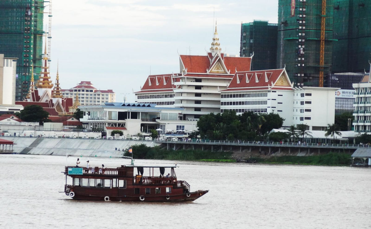 Wooden boat sailing past the Phnom Penh skyline