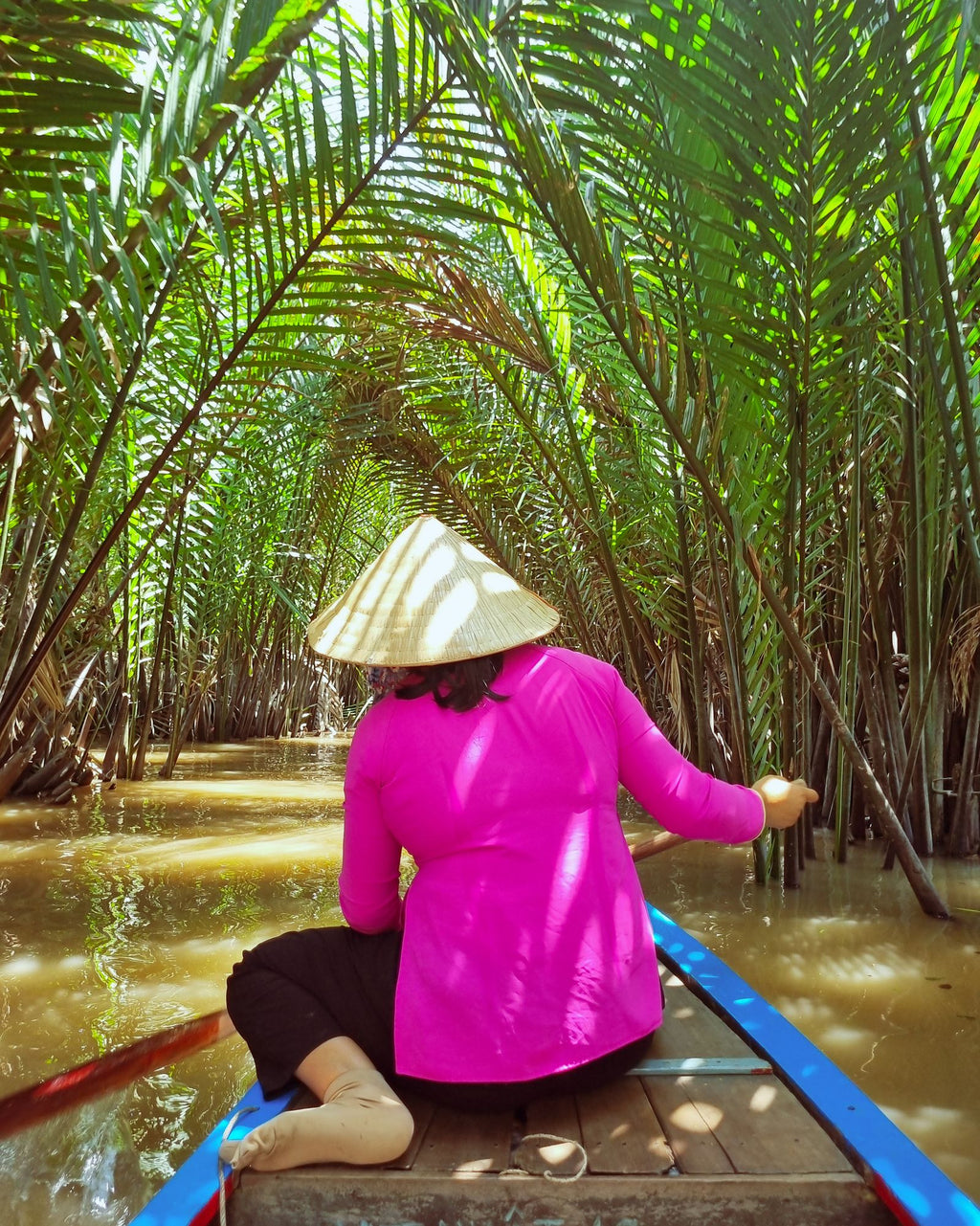 Woman rowing through palms in the Mekong Delta