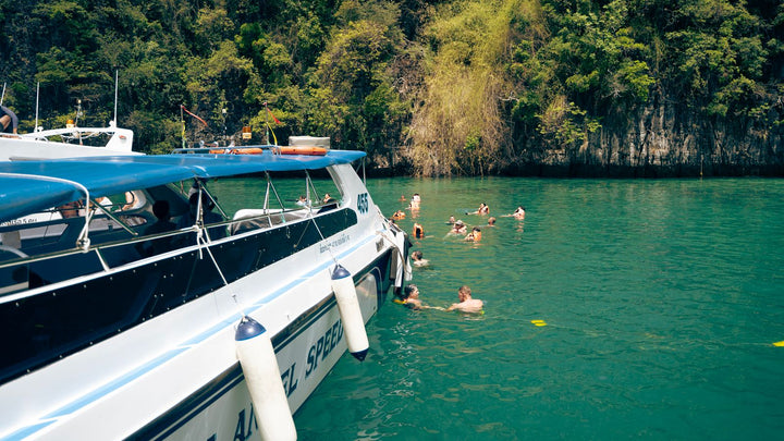 Swimmers near a speedboat in clear Thai water