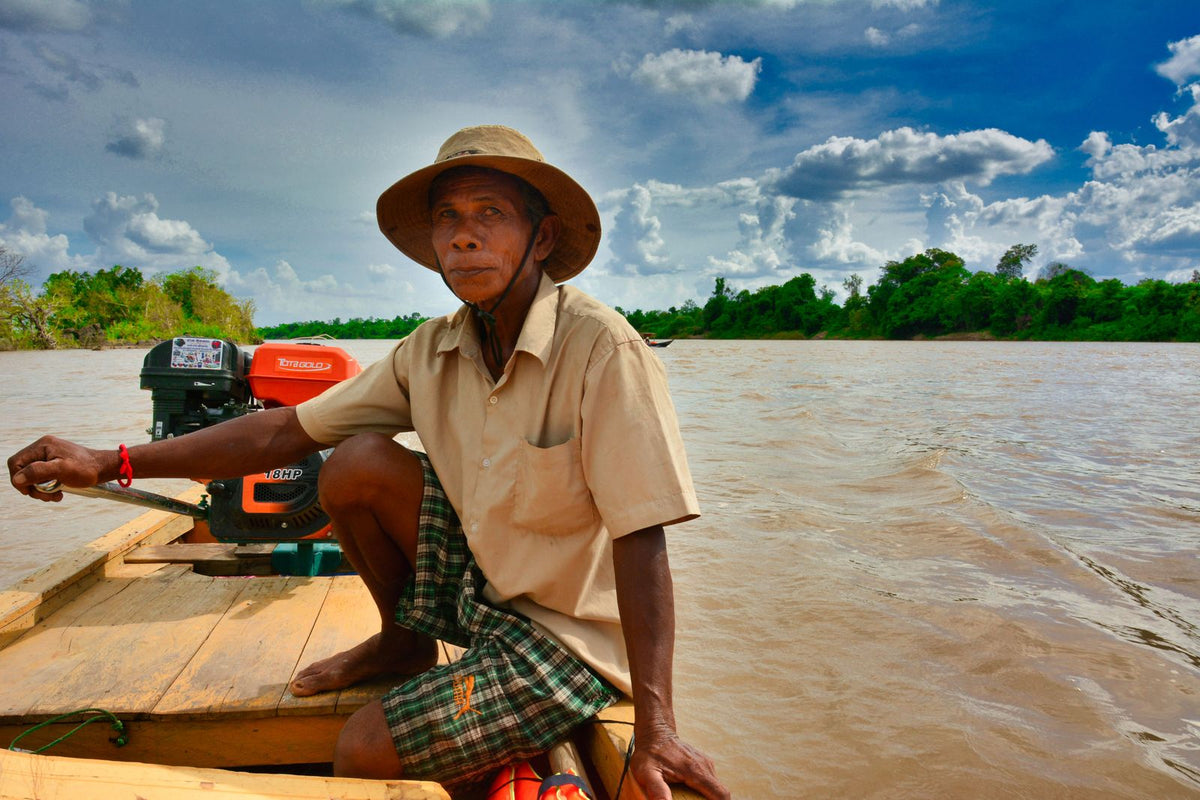 Cambodian fisherman in a wooden boat on the Mekong River