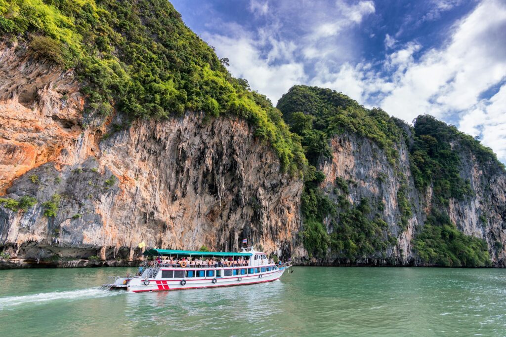 Home A boat cruise offers breathtaking views of lush cliffs under a bright blue sky.