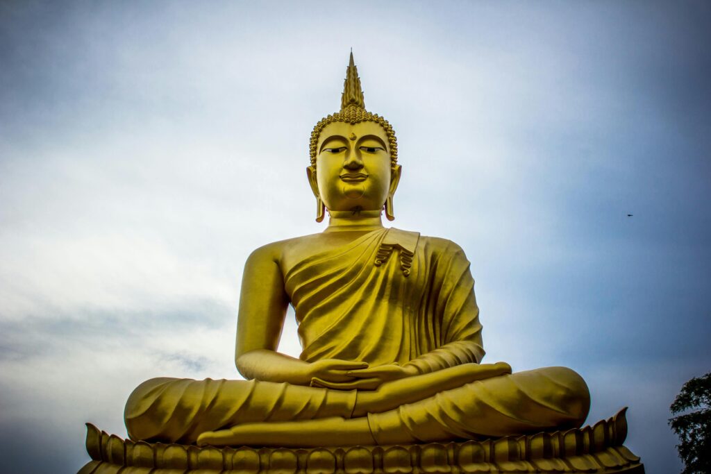 Home A majestic golden Buddha statue against a serene blue sky, symbolizing peace and spirituality.